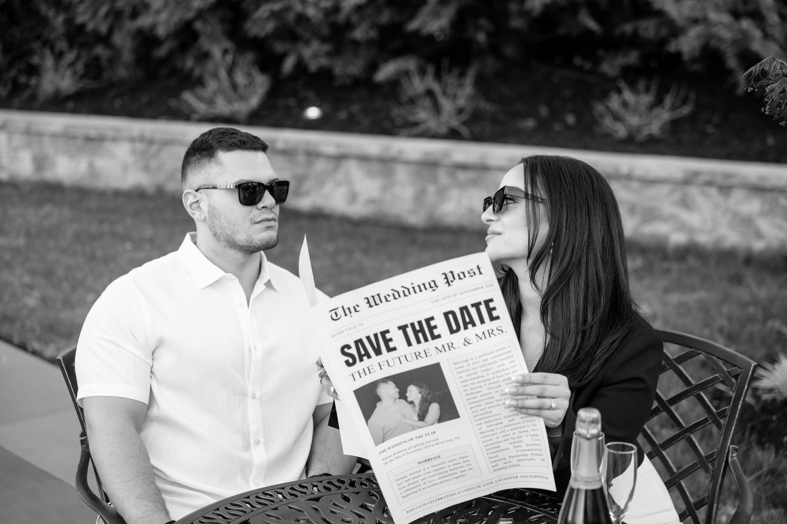Black and white photograph of the couple holding their save the date newspaper