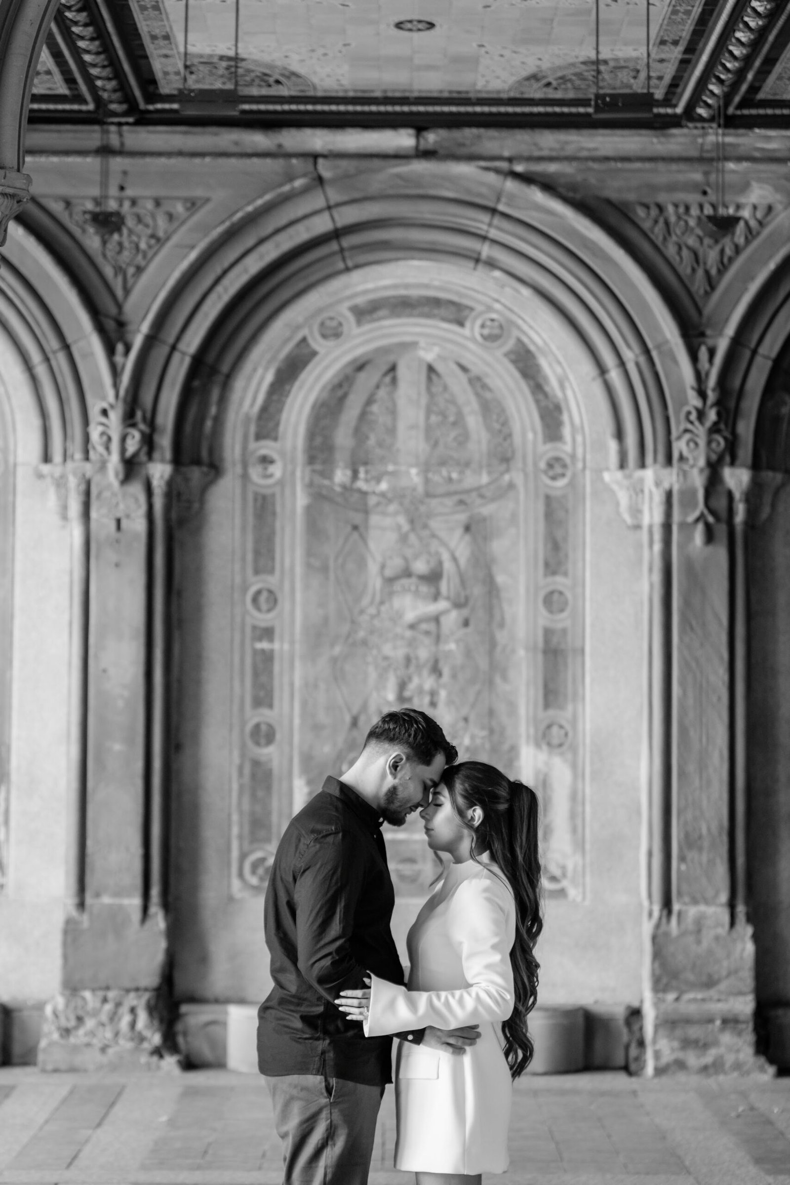 Black and white photograph of the couple kissing in an archway