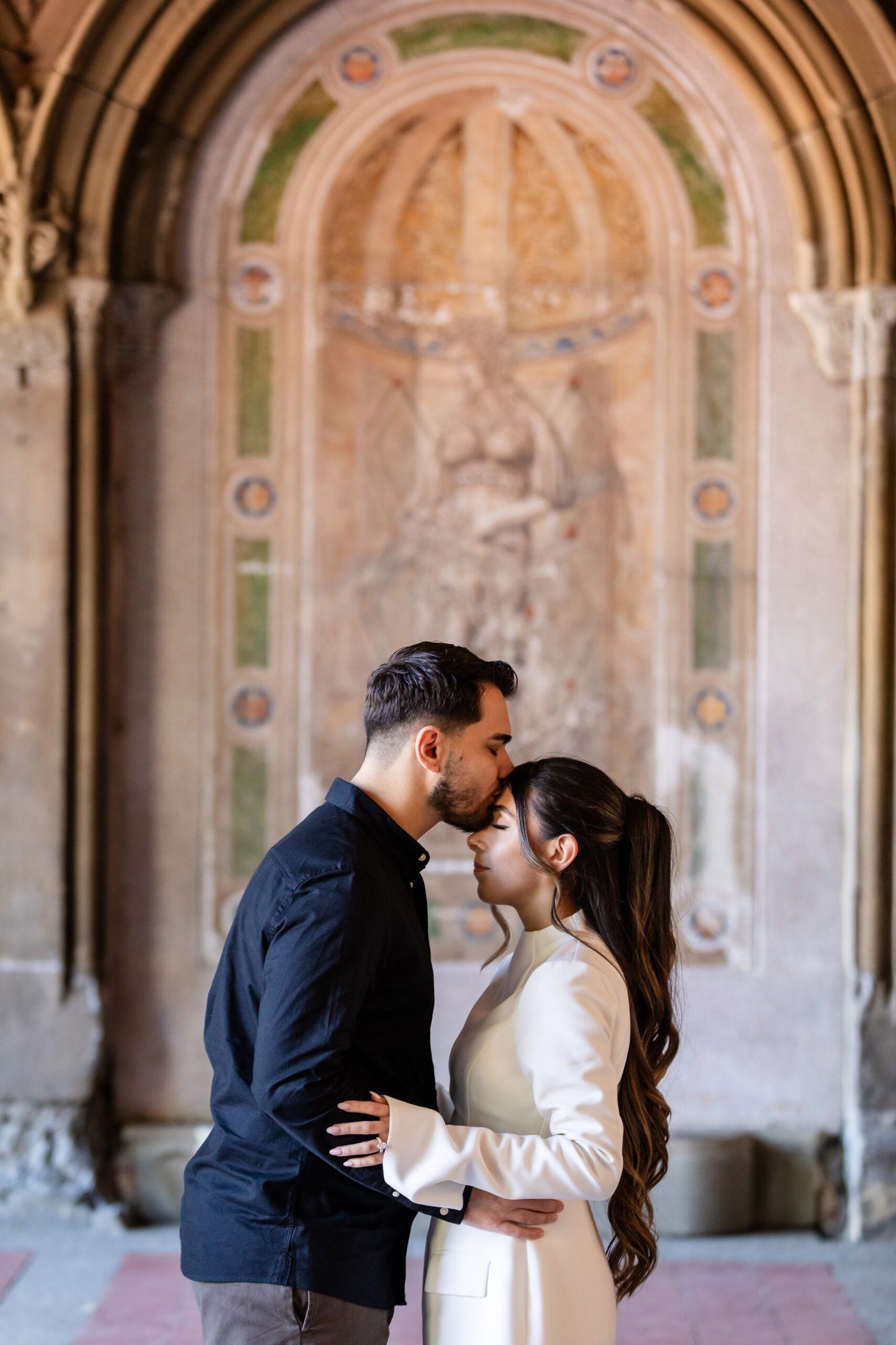 Couple sharing a kiss beneath a stone archway