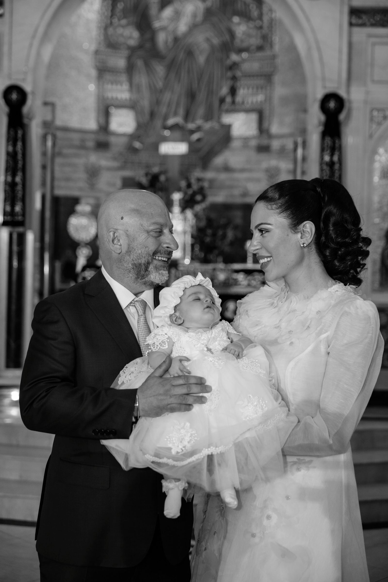 Black and white photograph of a baby held in a christening gown