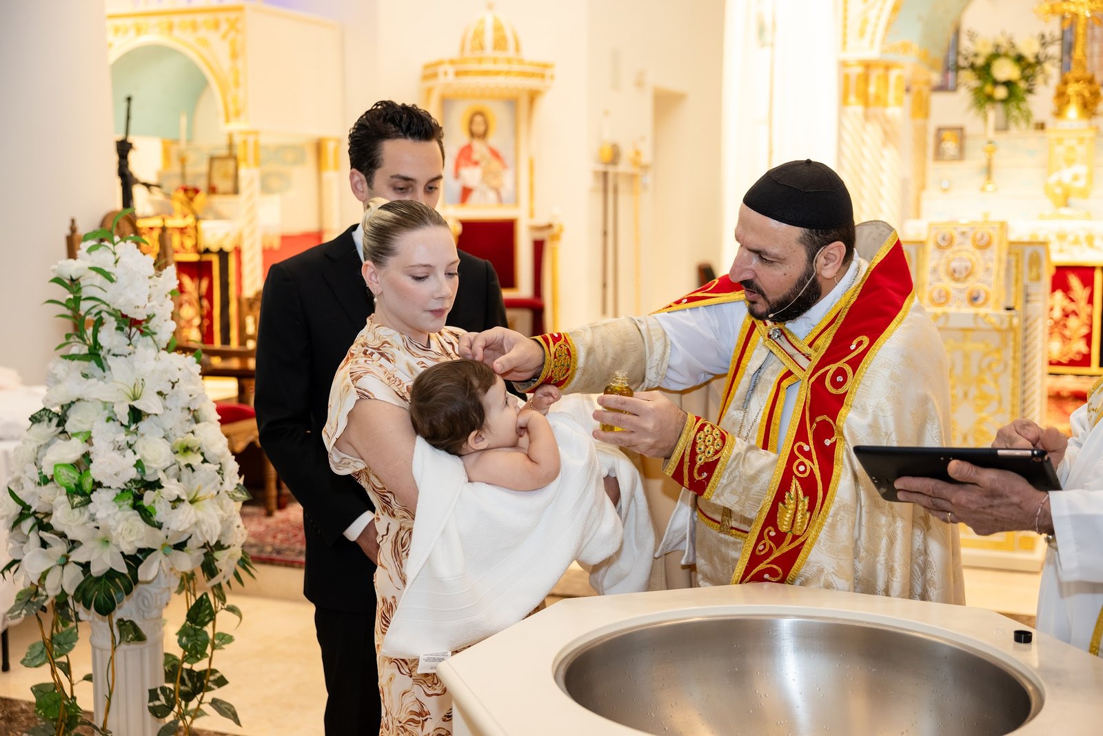 Baby being baptised at the font by the priest