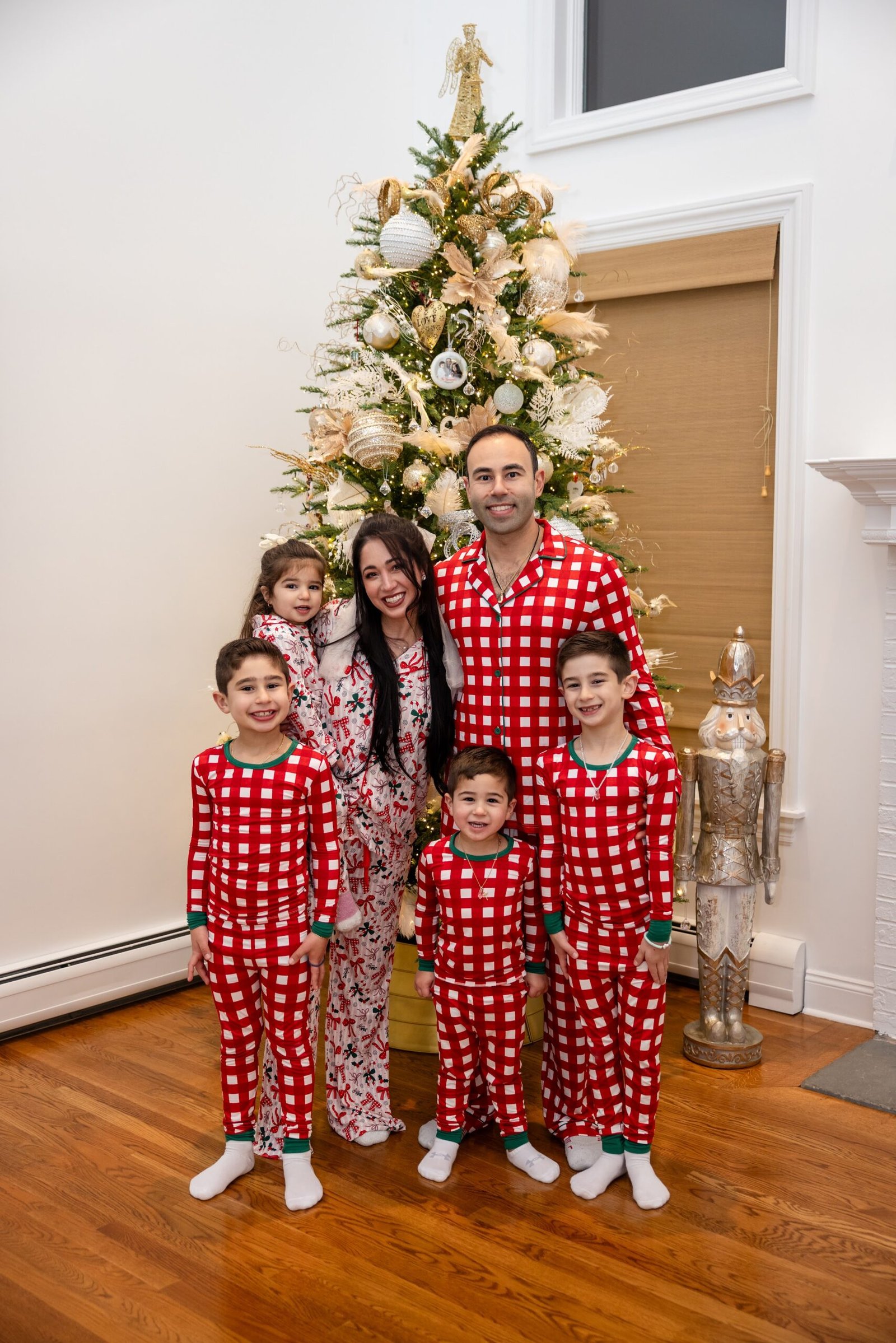 Large family in matching pyjamas beside the Christmas tree