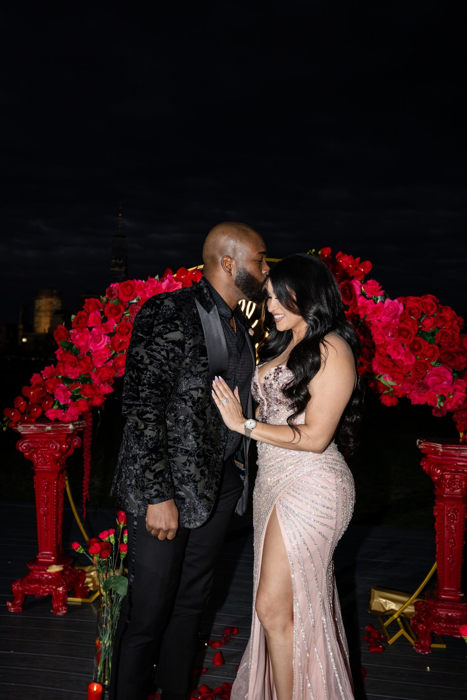 Couple embracing beside the illuminated rose arch